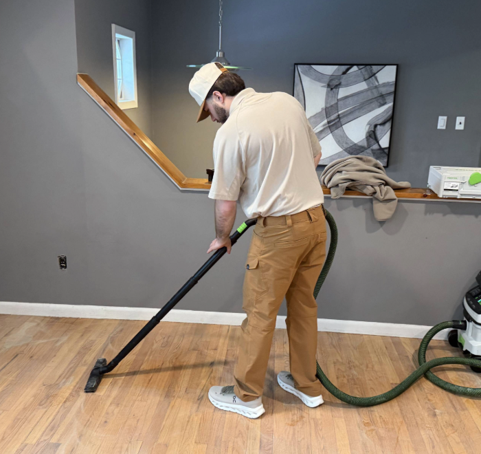 Professional hardwood floor preparation using vacuum before recoating process in North Jersey home